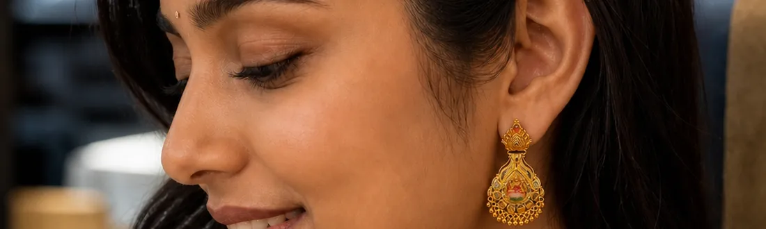 A woman wearing gold temple earrings in a warmly lit interior.